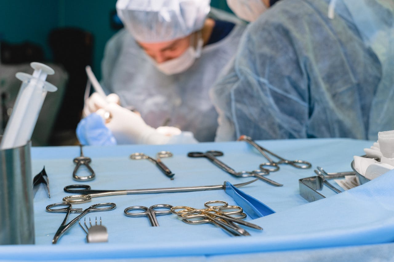 Close-up of surgical instruments on table with surgeons in the background preparing for surgery.